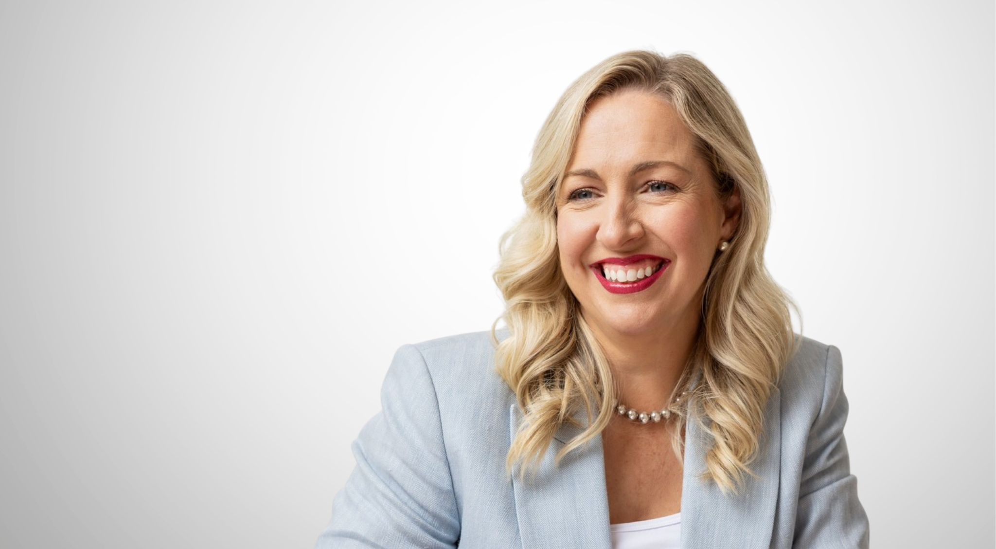 Blonde female in light blue blazer smiles at the camera